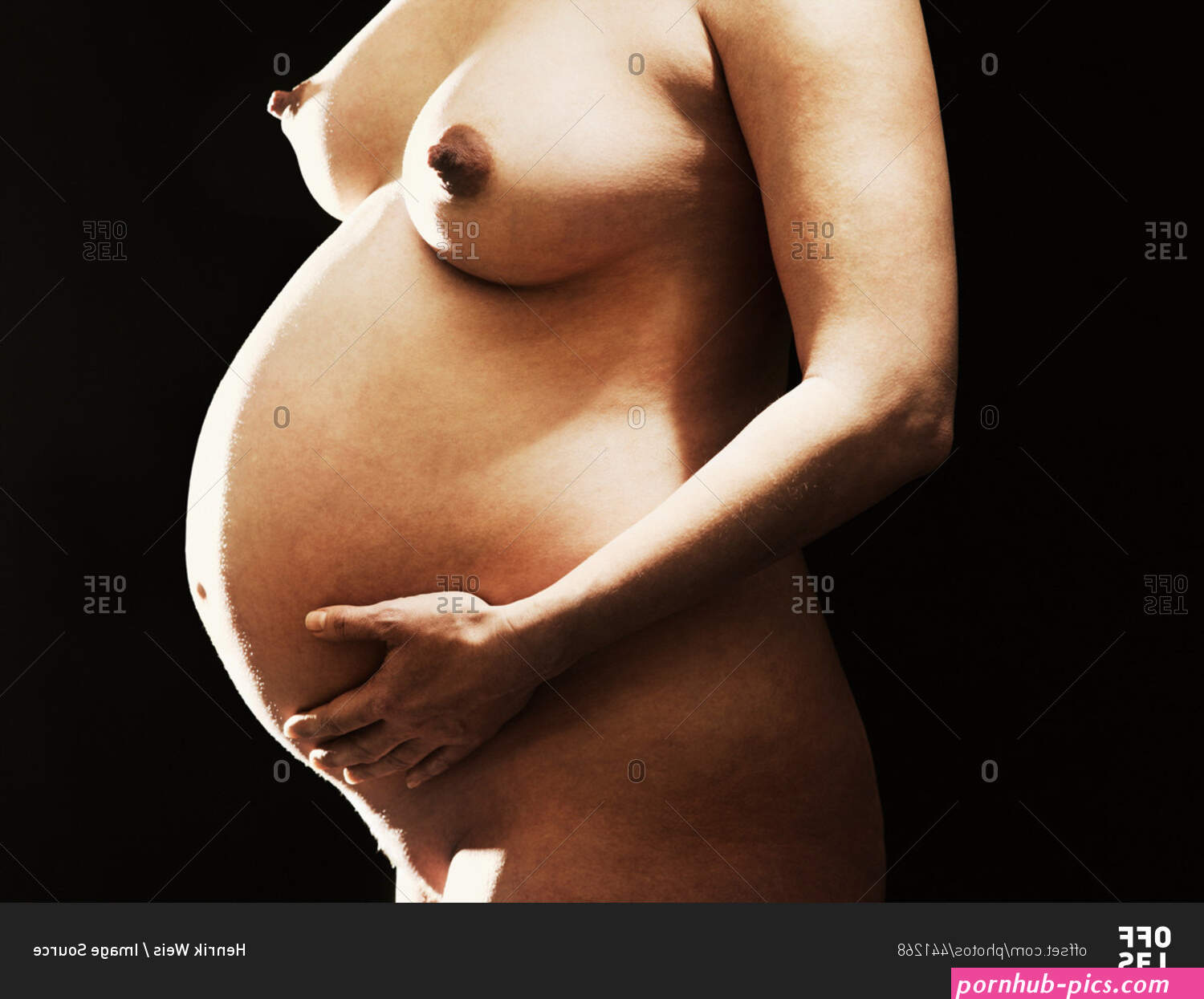 Nude pregnant woman holding her belly stock photo