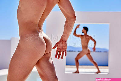 Body of muscular, naked caucasian man posing outside. Butt of nude male model, posing in front of a white wall. Strong, sensual man flaunting toned body standing in a cut out wall