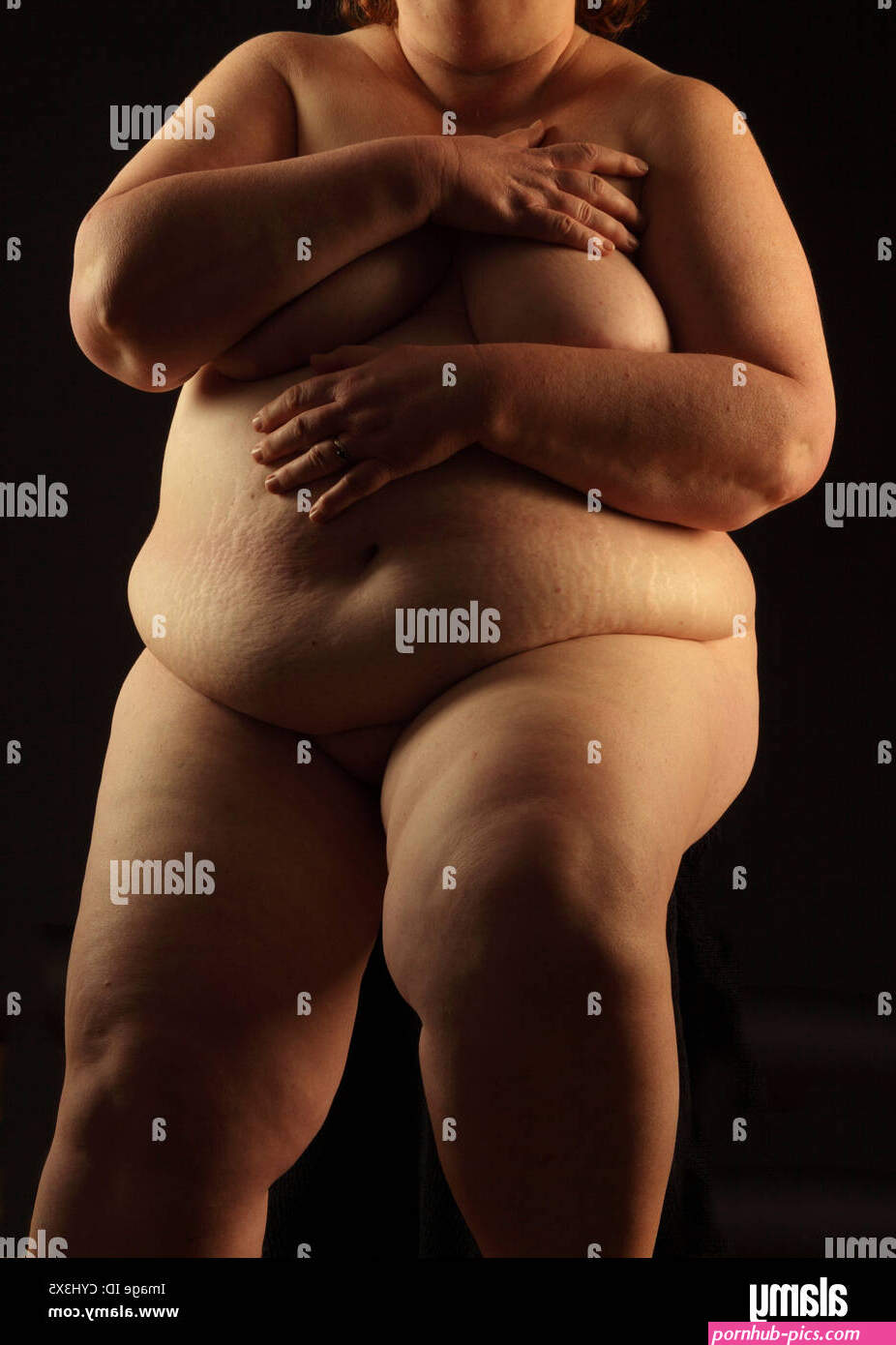 Obese naked woman seated on a black background Stock Photo
