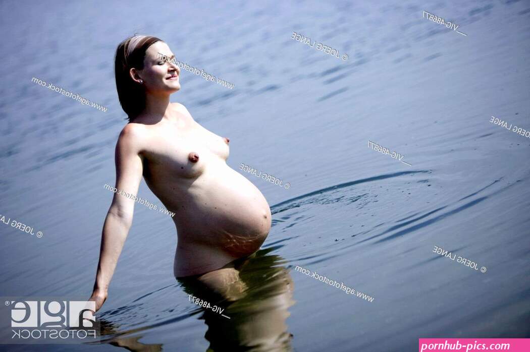A pregnant woman is bathing nude in a lake.
