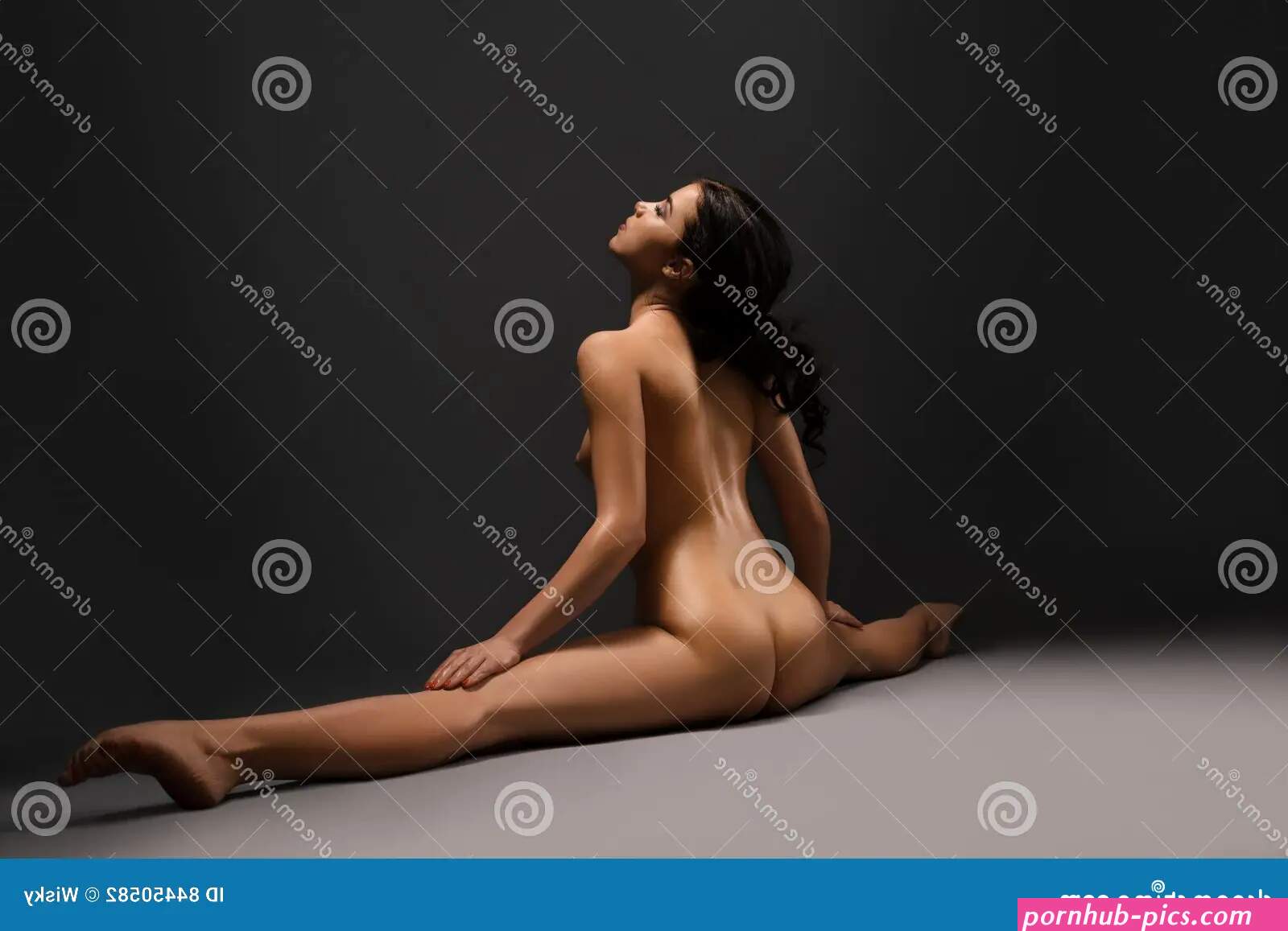 Beautiful Naked Woman Doing Splits at Dark Studio Stock Photo