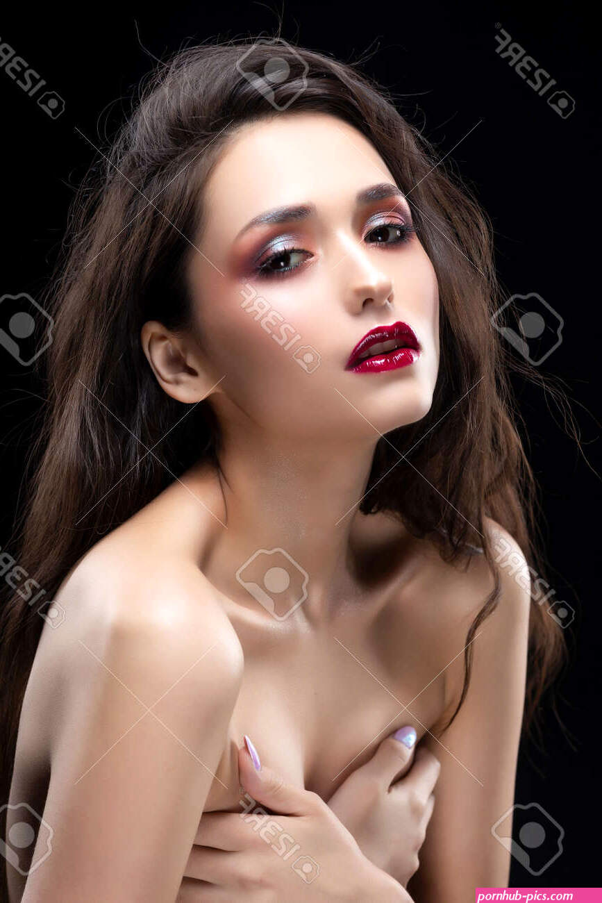 Portrait Of A Beautiful Glamorous Brunette Girl Sensually Covers Her Naked Breast With Her Hands. Shimmering Makeup Red Lips. Healthy Smooth Skin. Isolated On Black. Copy Space. -