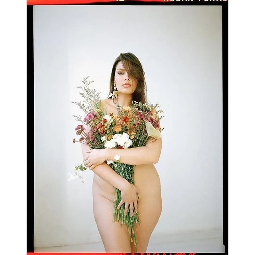 Candice Huffine cobre o corpo nu com buquê de flores