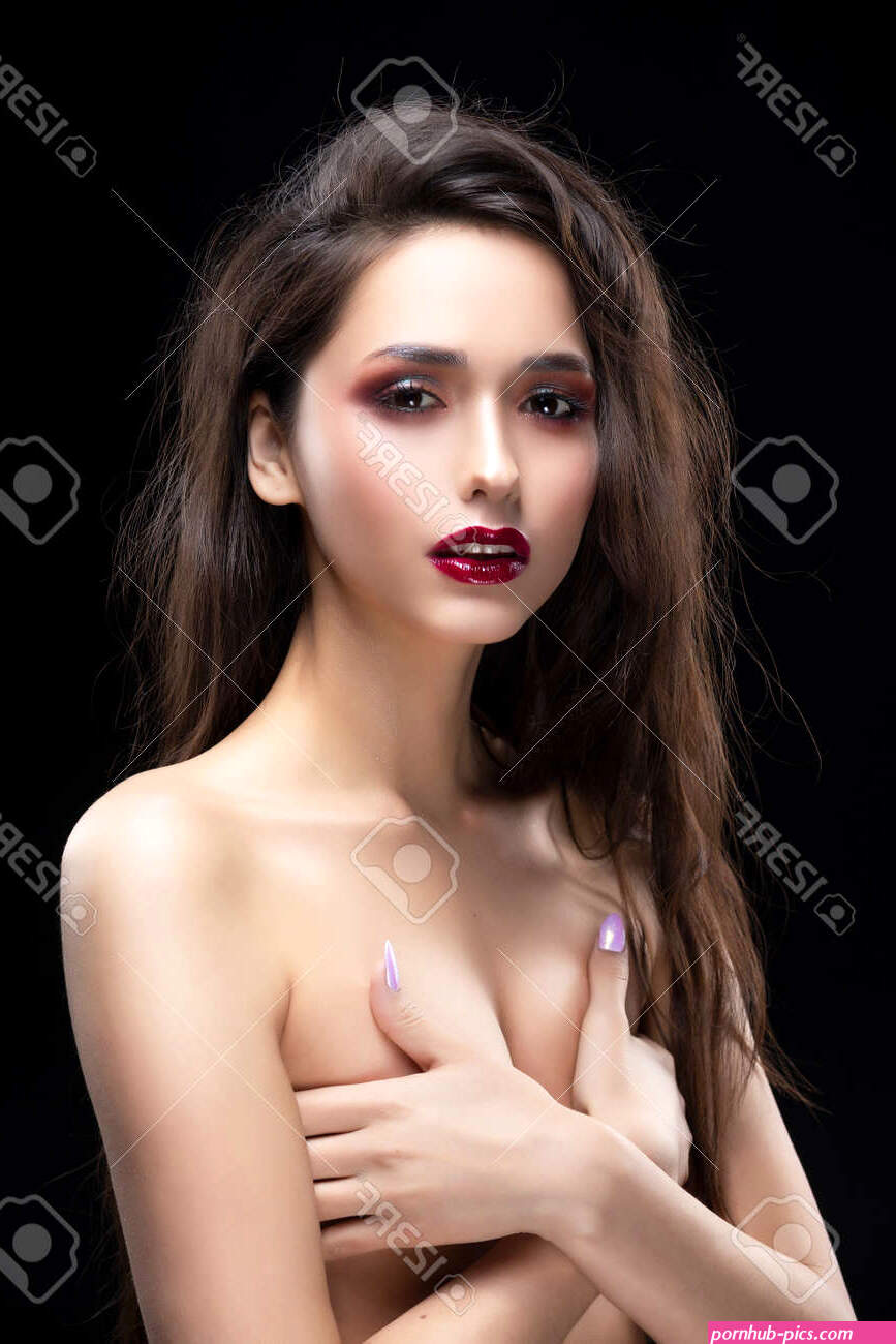 Portrait Of A Beautiful Glamorous Brunette Girl Sensually Covers Her Naked Breast With Her Hands. Shimmering Makeup Red Lips. Healthy Smooth Skin. Isolated On Black. Copy Space. -