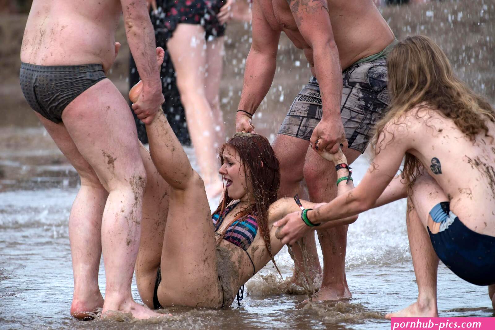 Naked girls wrestle in muddy water and straddle each other at Woodstock music festival in Poland