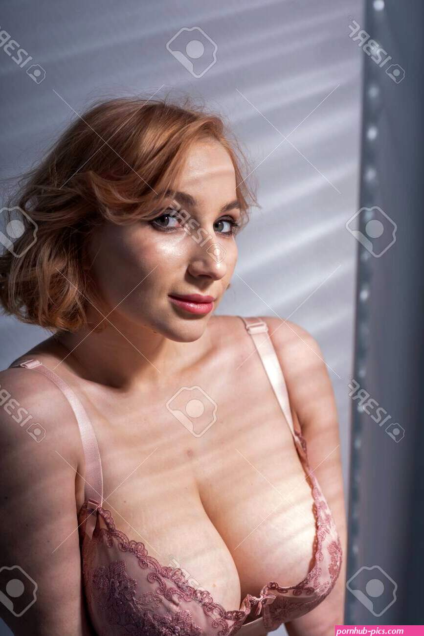 A Beautiful Young Woman With Very Large Natural Breasts Is Standing By The Window With Shutters. A Girl In Pink Lace Shows A Beautiful Figure Next To A White Screen. Huge Female