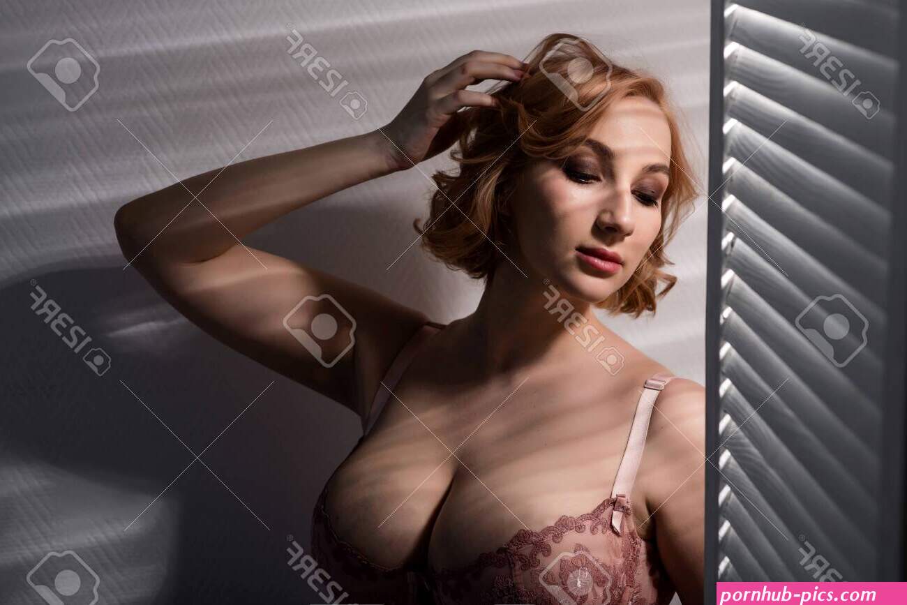 A Beautiful Young Woman With Very Large Natural Breasts Is Standing By The Window With Shutters. A Girl In Pink Lace Shows A Beautiful Figure Next To A White Screen. Huge Female