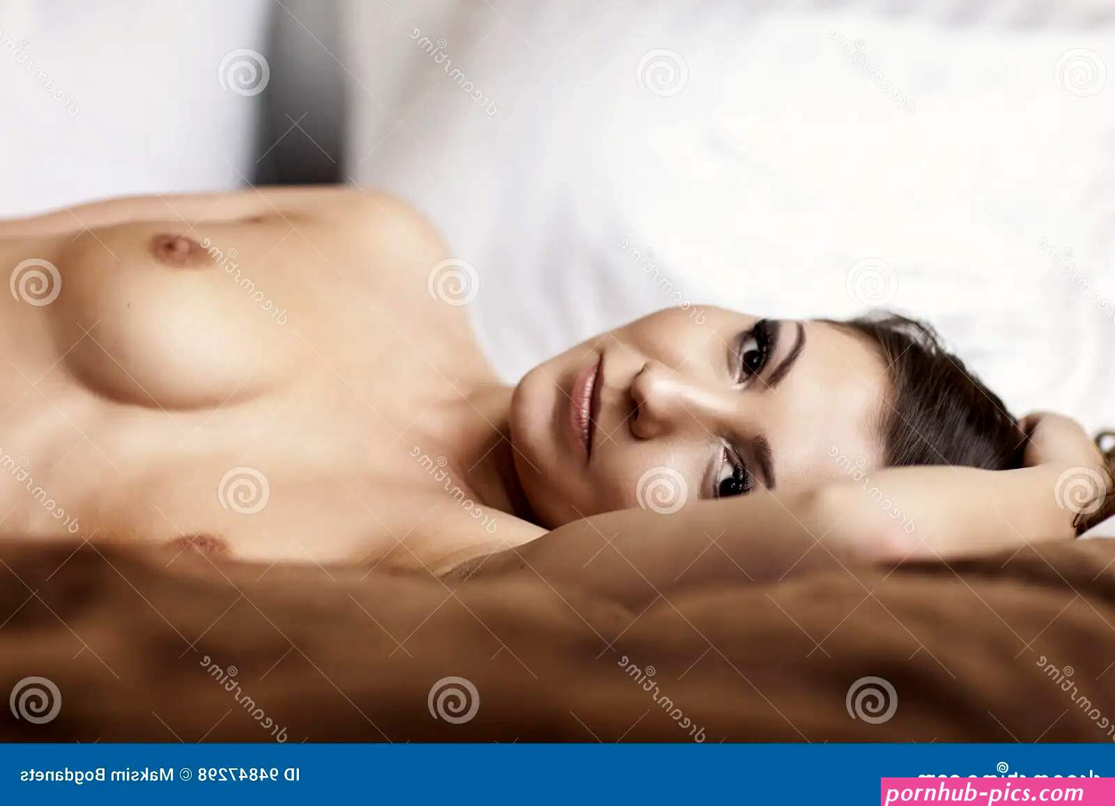 Beautiful Brunette Woman Lying in Bed with Naked Breasts Stock Photo