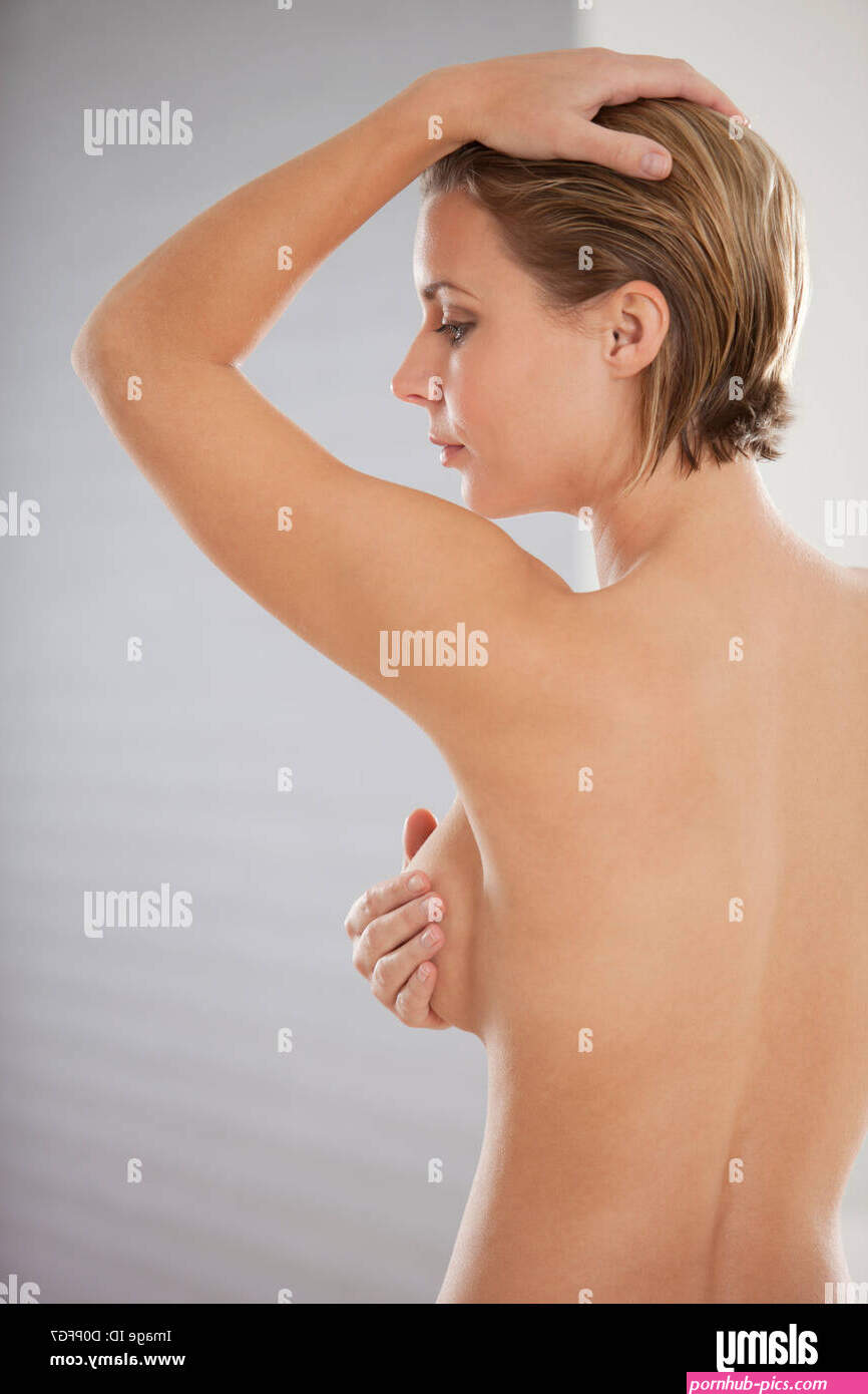 Naked young woman self examining her breasts for cancer Stock Photo