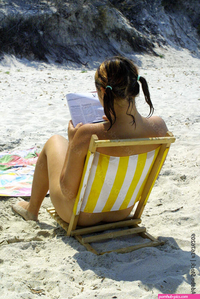 Nude girl reading on beach Stock