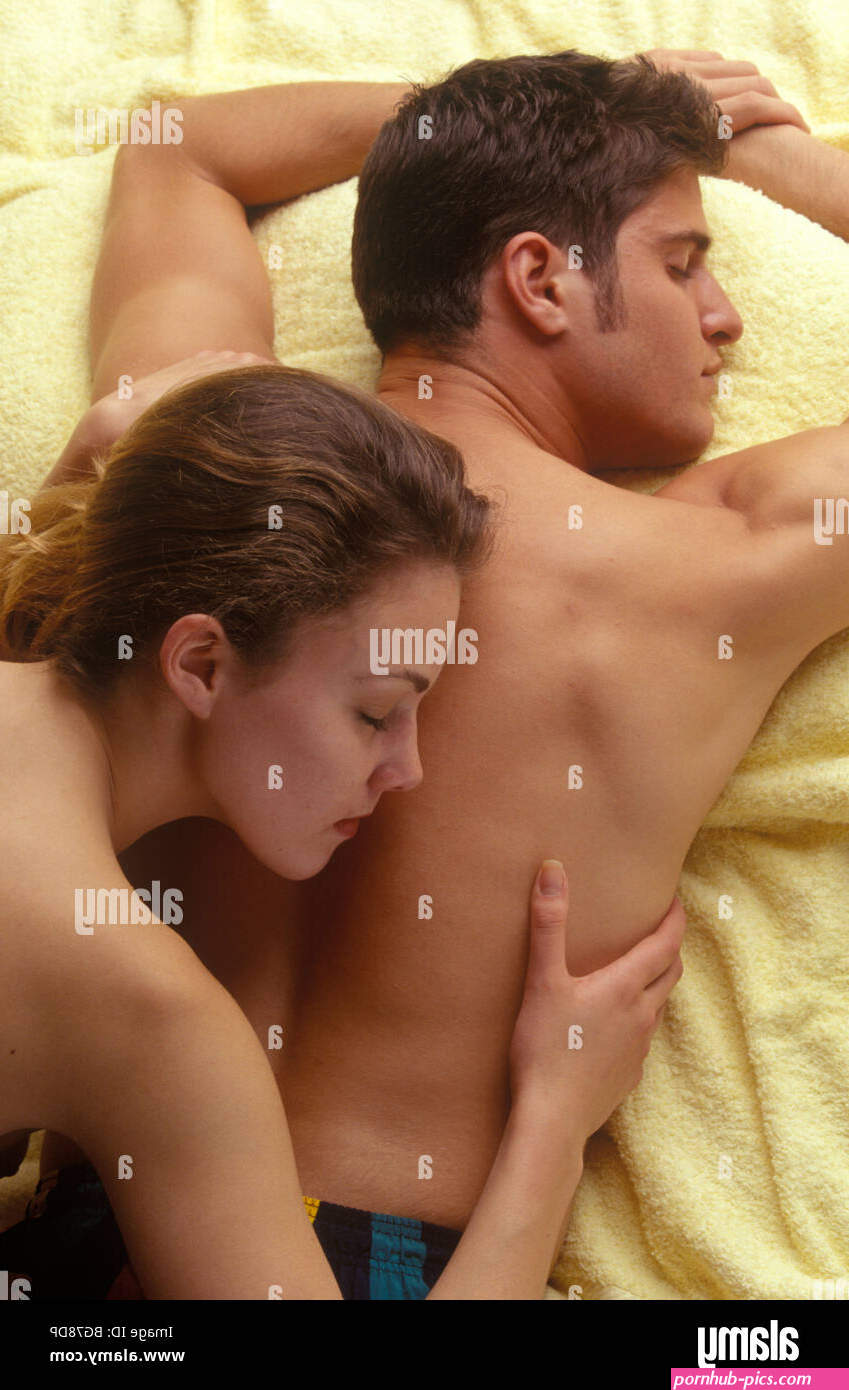 back view of a young couple on a towel partially naked cuddling Stock Photo