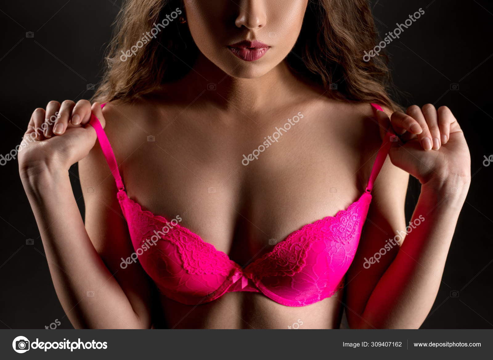 Brunette takes off her bra while looking at camera Stock Photo Wisky 309407162