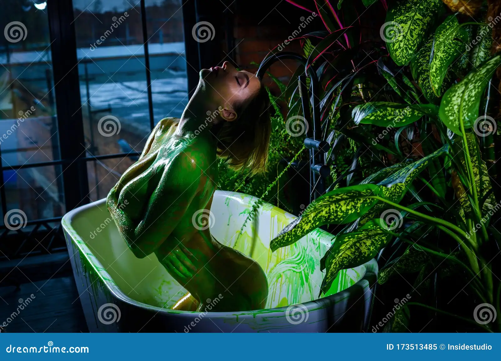 Beautiful European Woman with Very Big Breasts Takes a Bath. Green Paint Flows Down the Naked Body of a Girl in the Stock Image