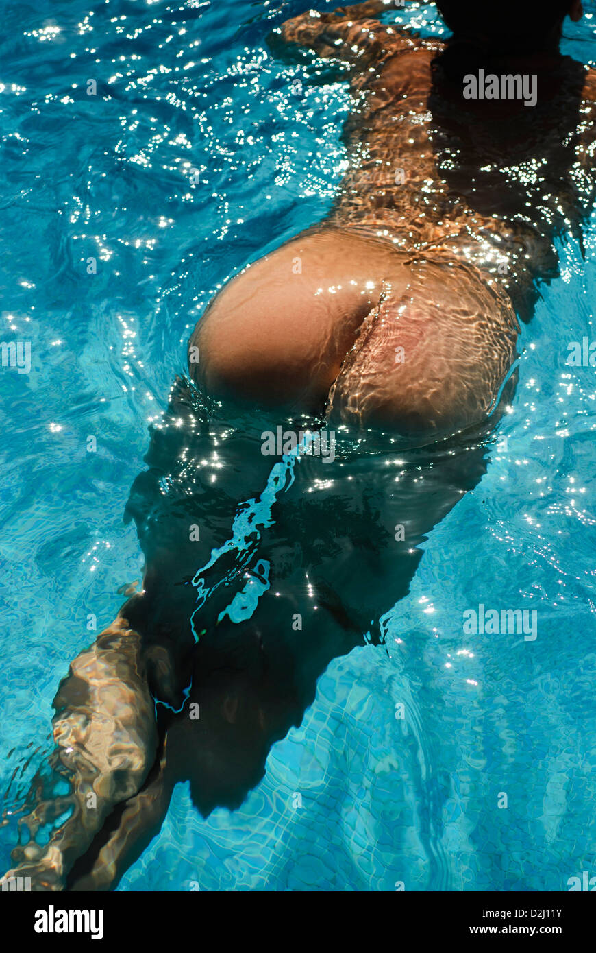 naked woman in her forties takes a bath in a blue outside swimming pool Stock Photo
