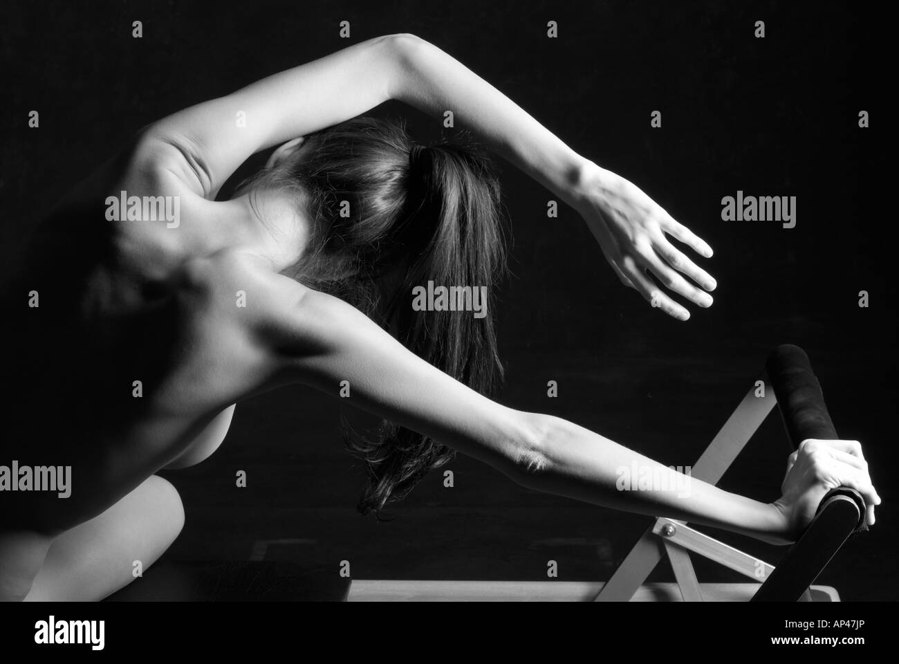 nude woman doing pilates stretching exercise black and white studio shot Stock Photo