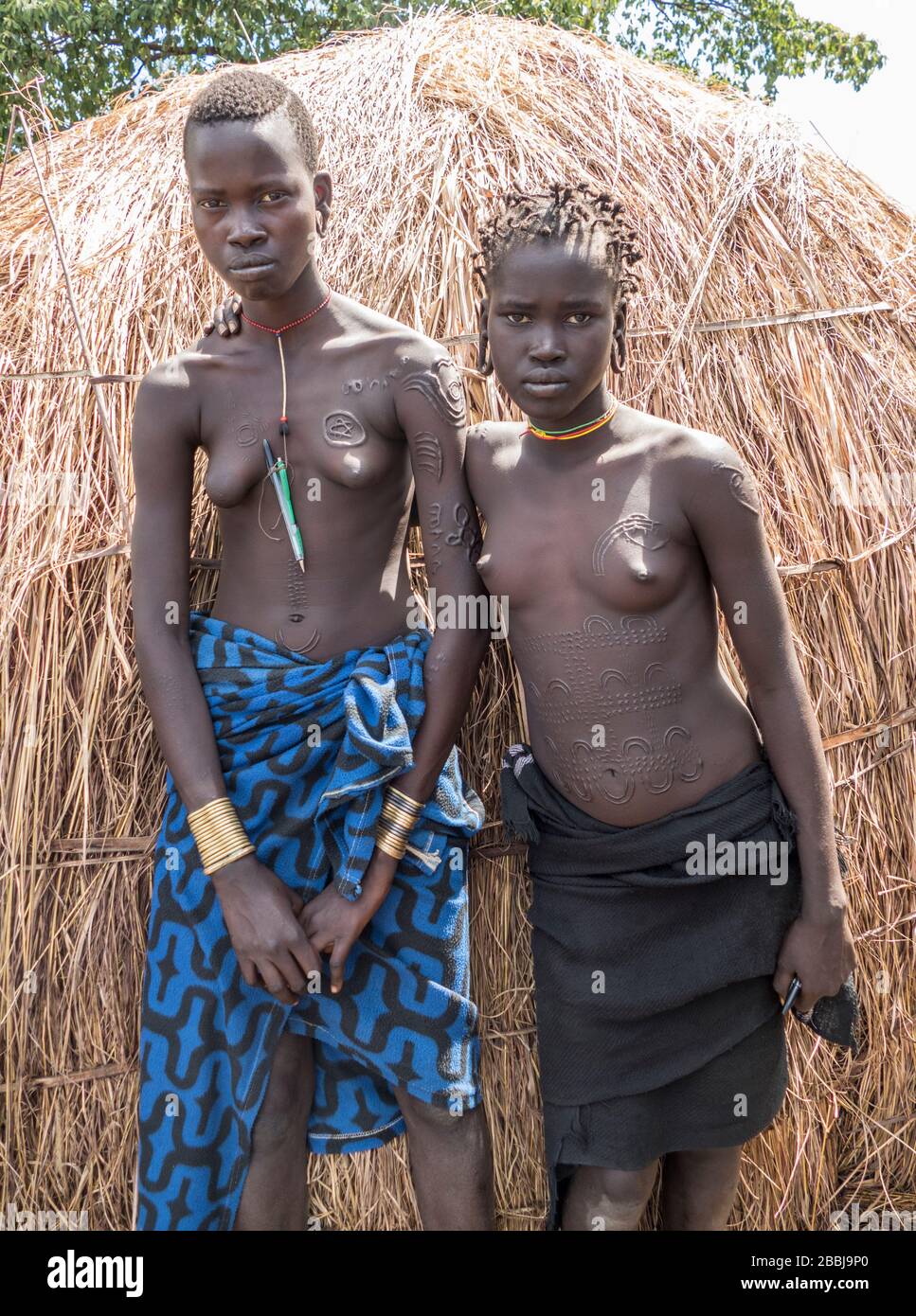 Two Traditional Young Mursi Tribe Women with Beauty Scarring and Wearing Tradtional Ornamentation in the Mursi Village in the Omo Valley in Southern E Stock Photo