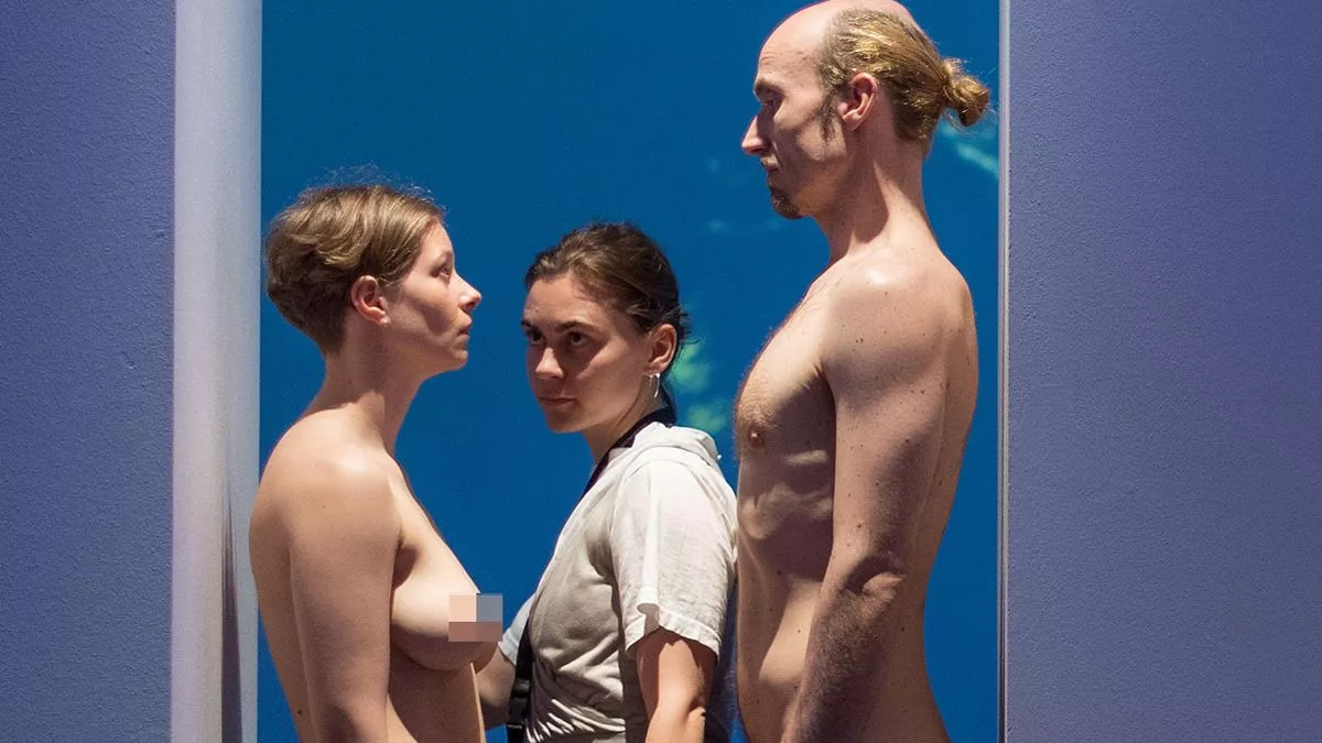 Art gallery visitors must squeeze between naked man and woman standing in door