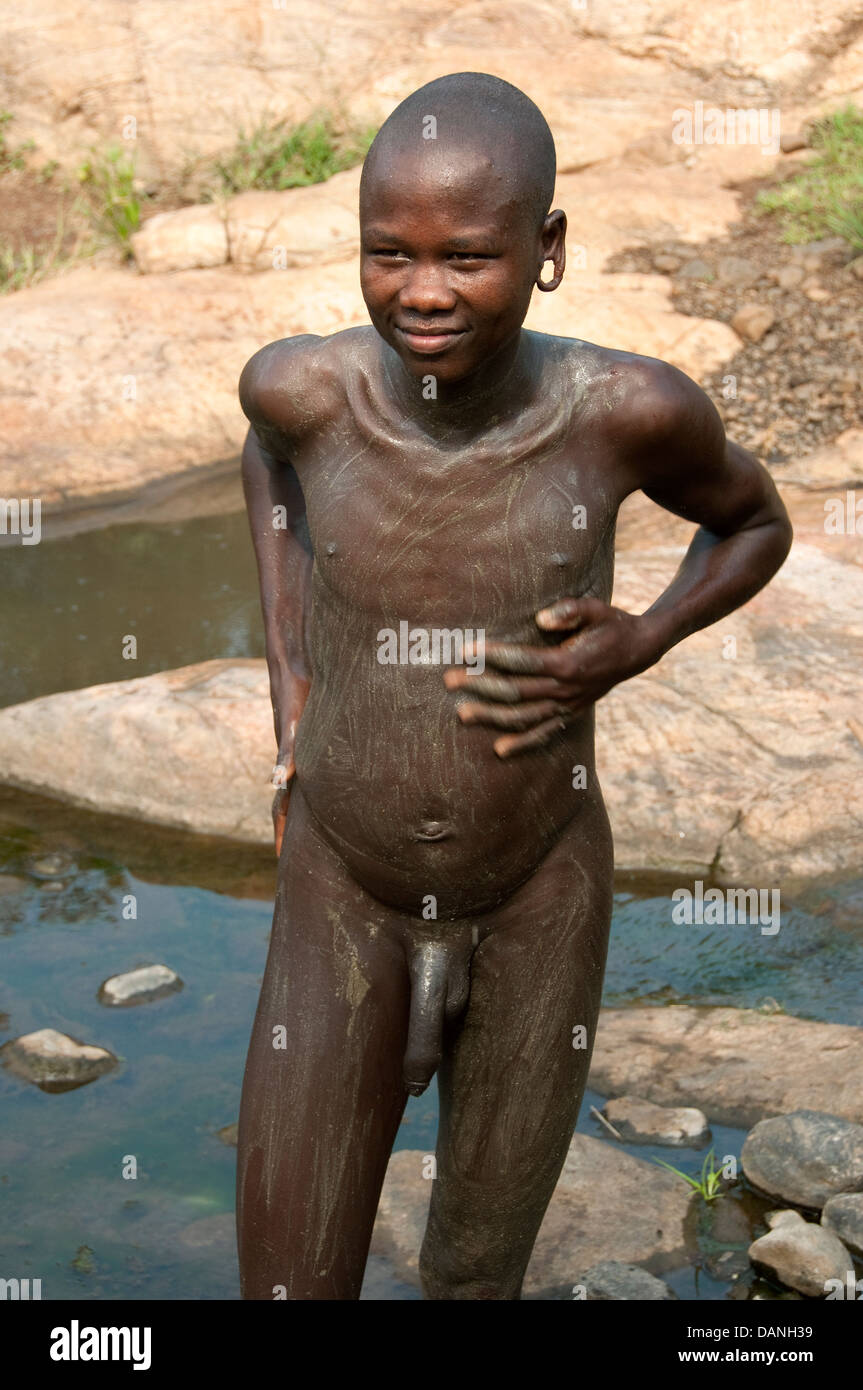 A Suri Surma naked young man body painting himself with mud Ethiopia Stock Photo
