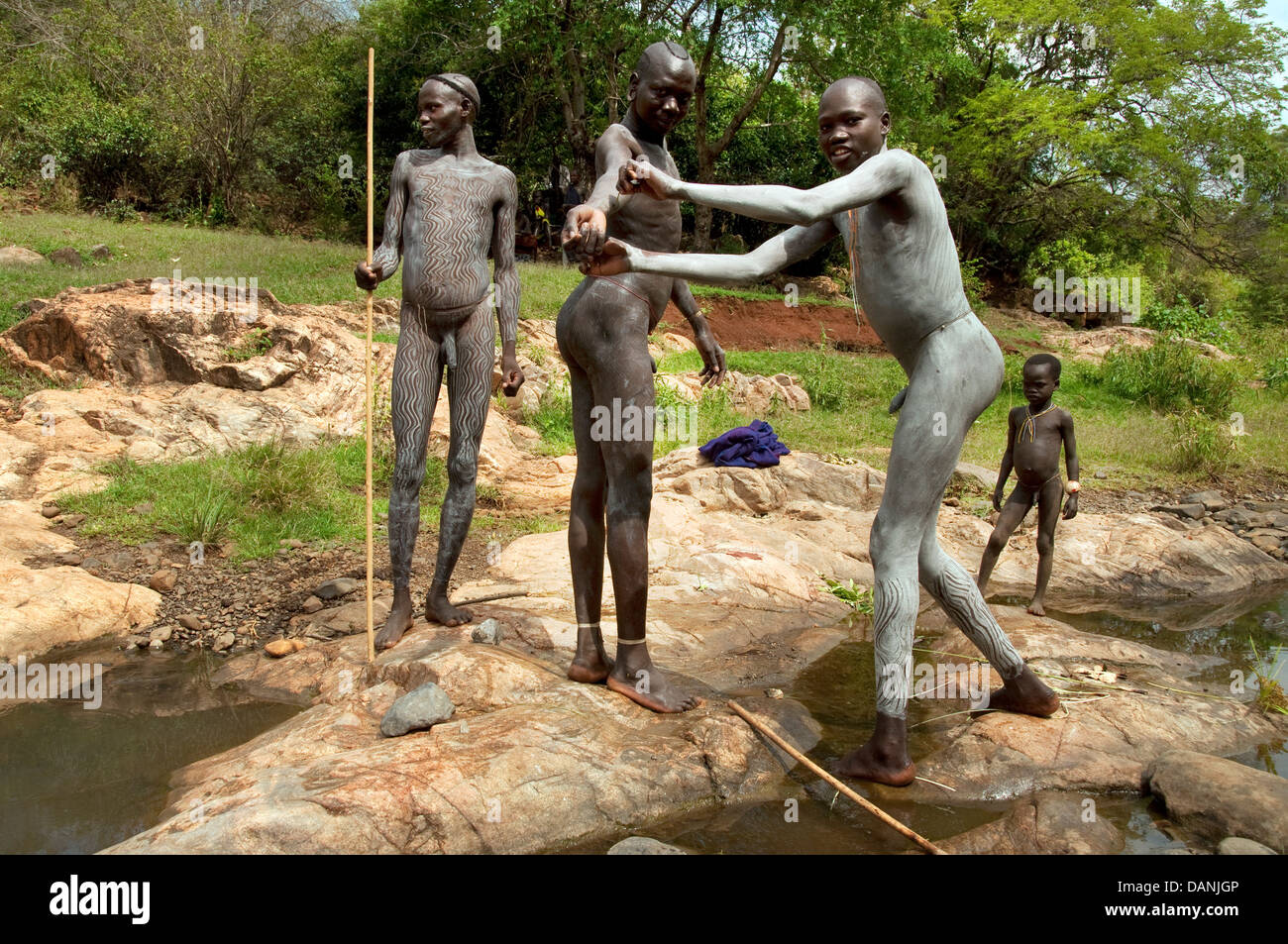 Three Suri Surma naked young men body painting with mud Ethiopia Stock Photo