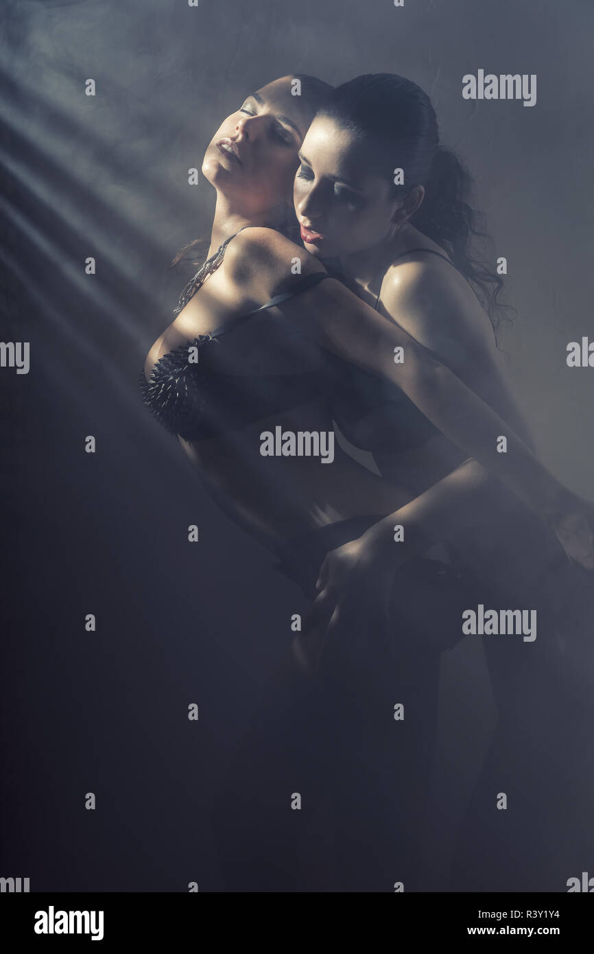 Two beautiful sexy lesbian women in erotic foreplay game on dark background Stock Photo