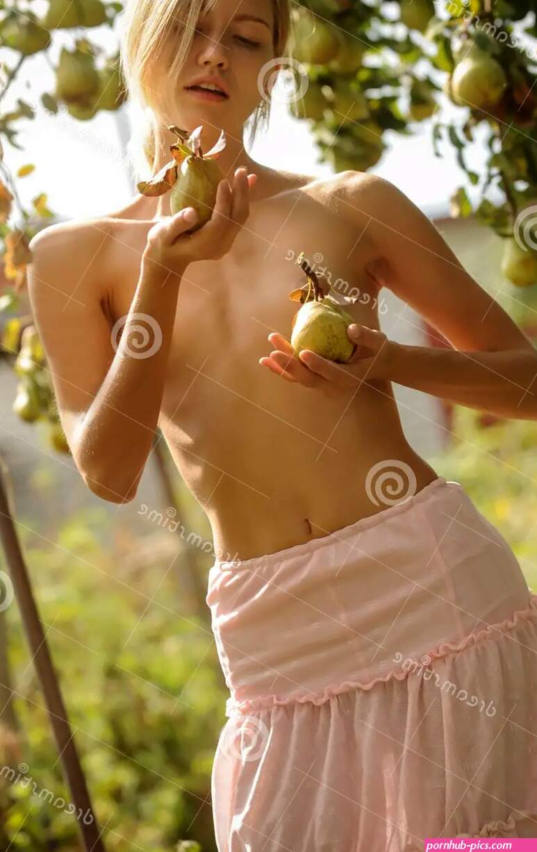 Semi-nude Girl Against a Background of Pear Trees with a Ripe Harvest. he Covers His Small Tits with Two Ripe Pears Stock Image