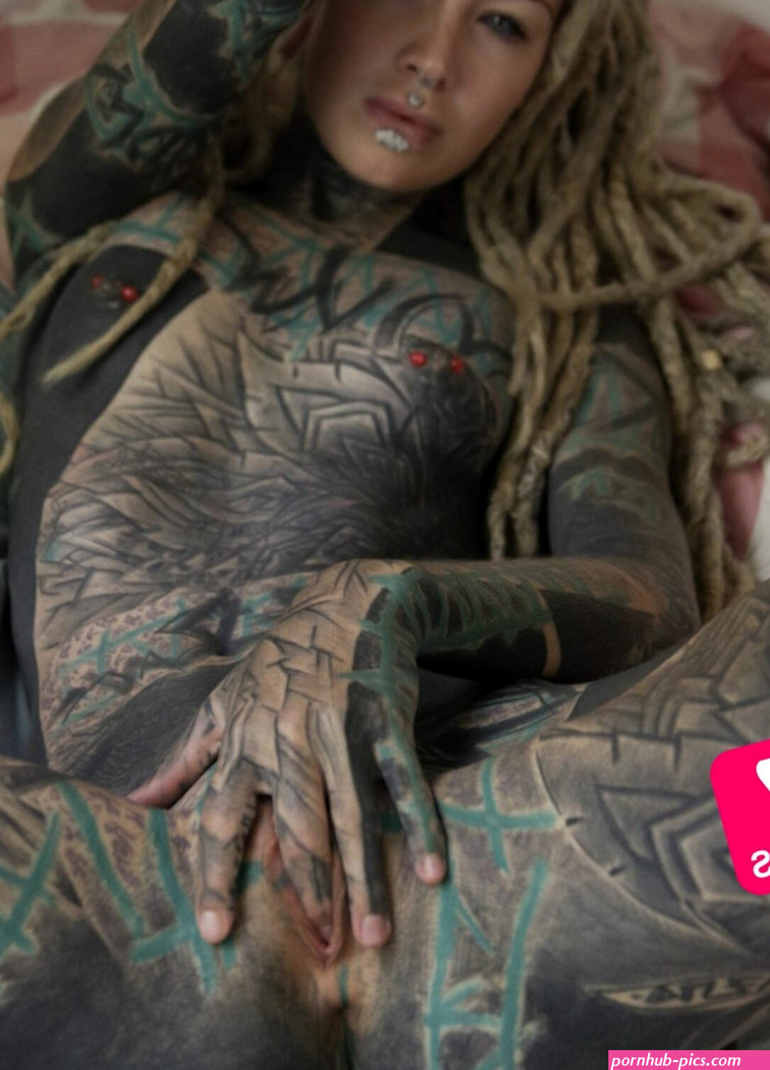 Heavily tattooed girl Anuskatzz slips a finger in her naked pussy