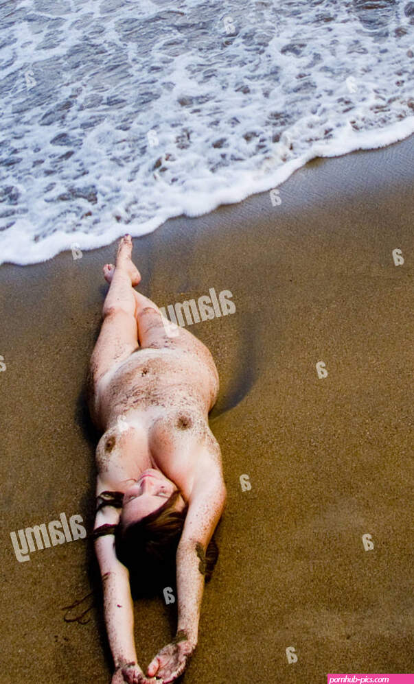 Nude sexy woman laying on Caribbean beach with waves around her and she is covered with sand Stock Photo