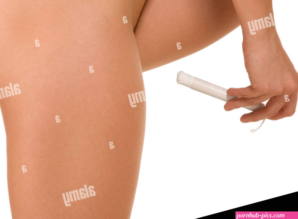 Tampon use. Close up of naked woman hips and her hand holding white vaginal cotton tampon preparing to insert it Stock Photo