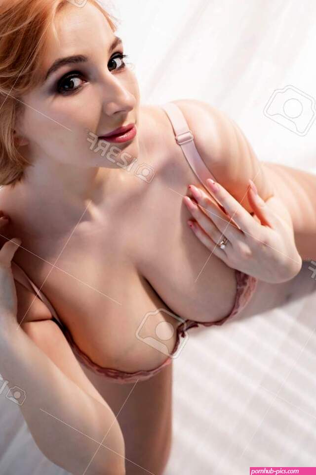 A Beautiful Young Woman With Very Large Natural Breasts Sits On Her Knees On The Light Floor. A Girl In Pink Lace Shows A Beautiful Figure. Top View. Huge Female Boobs. Stock