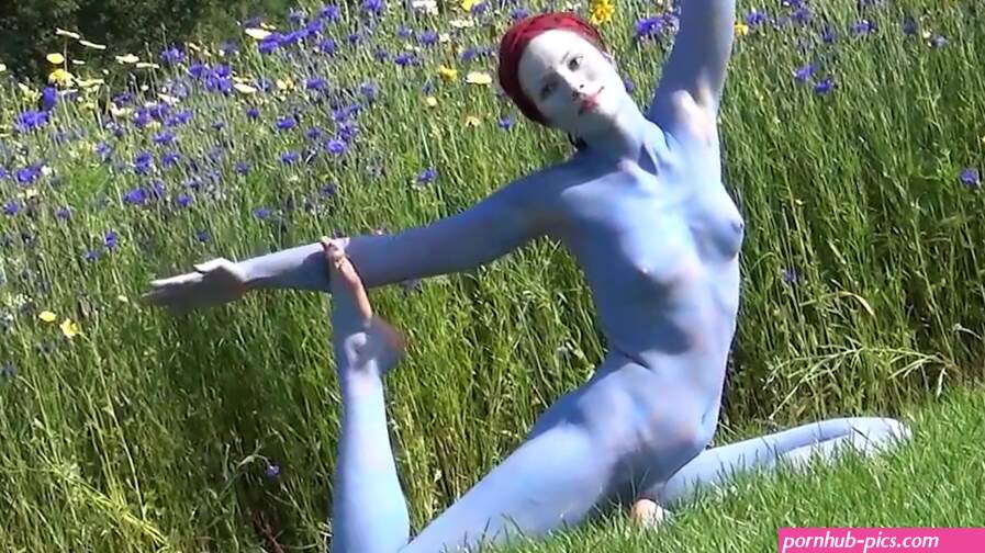 Flexible nude girl with body painting does naked yoga outside