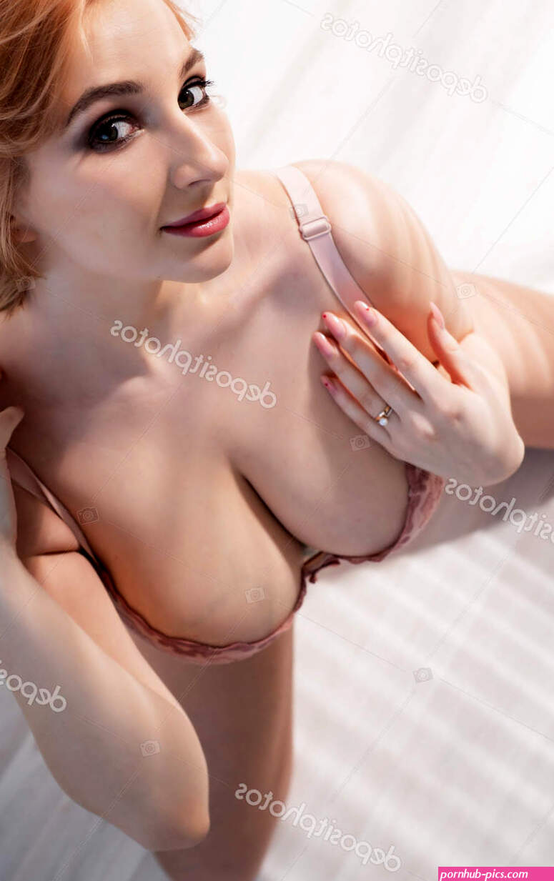 A beautiful young woman with very large natural breasts sits on her knees on the light