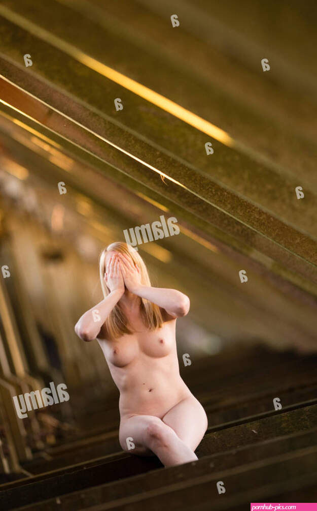 Healthy lifestyle and well-being: A naked nude young blonde woman sitting facing the camera with her hands covering her face exhibitionist exhibitionism Stock Photo