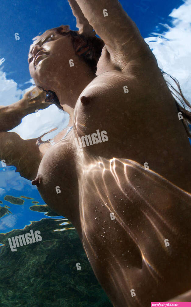 Underwater view of young Asian nude woman partially submerged sitting with hands behind head Stock Photo