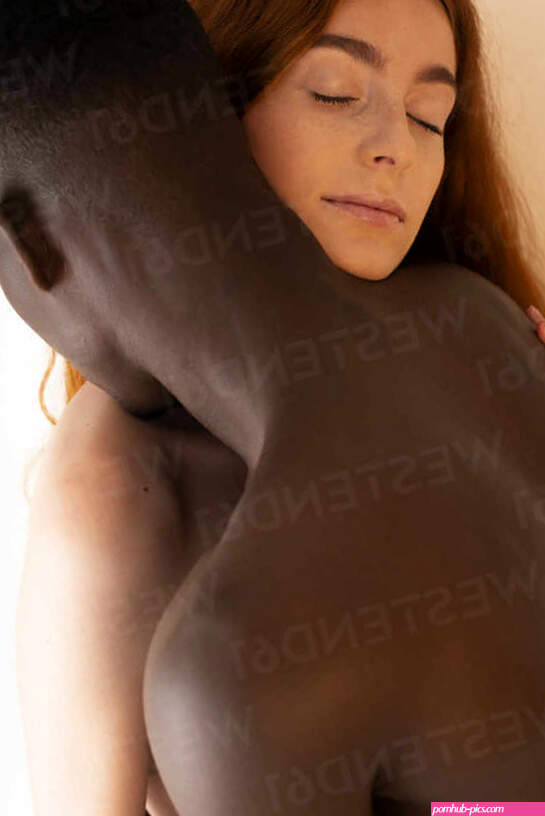 From below side view of multiethnic couple with naked torsos tenderly hugging on beige background stock photo