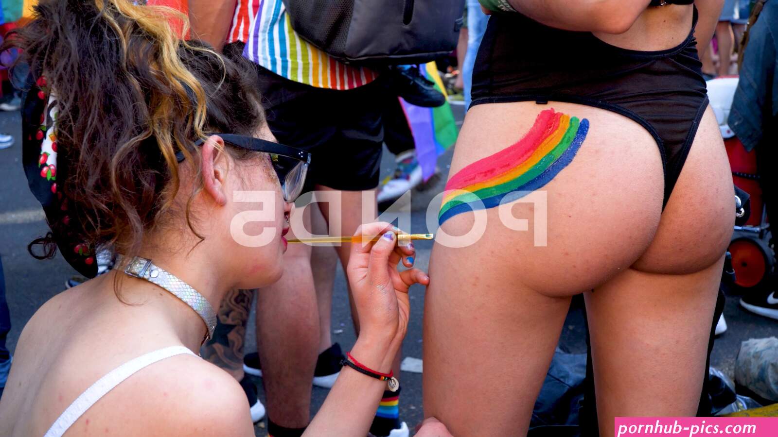 Woman freehand painting rainbow on naked...