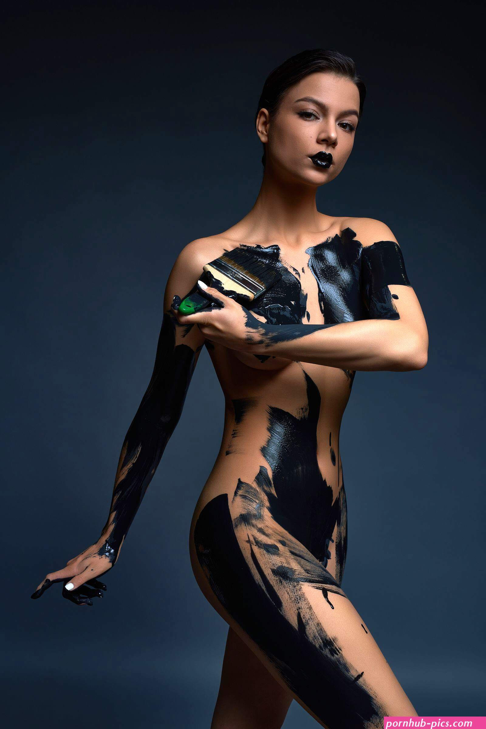 sensual slim young naked woman standing in dark studio and paint black color. Photographer Andrey Guryanov