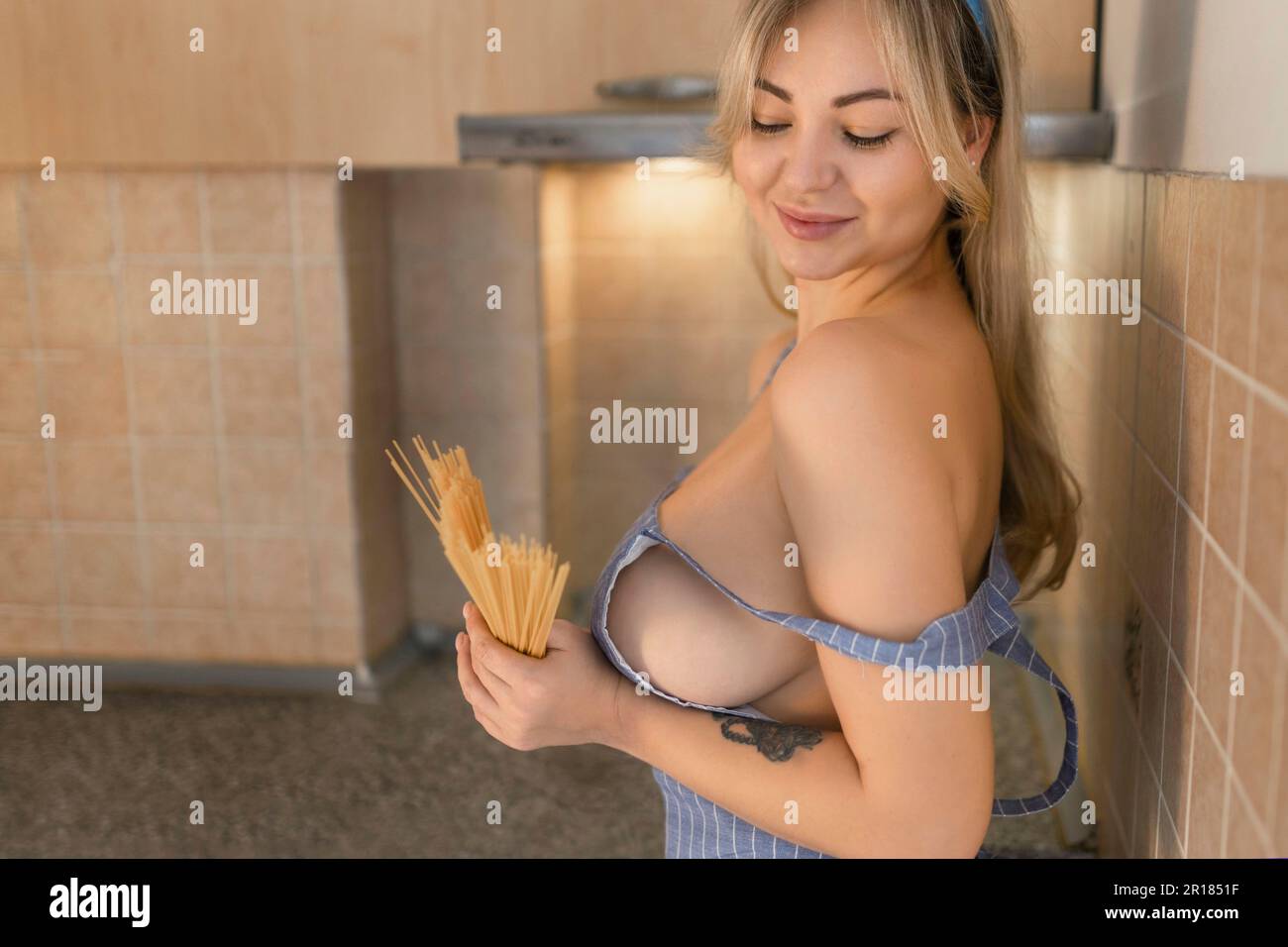 Sexy girl in apron with big breasts cooking Stock Photo